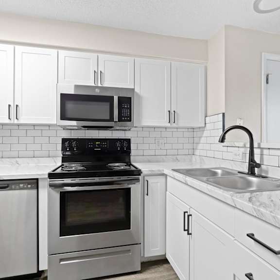 fully updated kitchen with white shaker cabinets, subway tile backsplash, black fixtures, and stainless steel appliances at 1443 elizabeth in denver, co