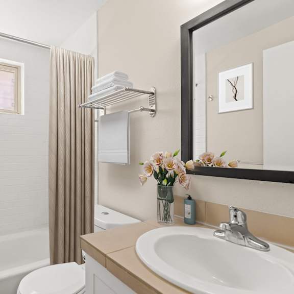 modern bathroom with a white tile shower, built-in tub, single vanity, and neutral-toned finishes at 1443 elizabeth in denver, co