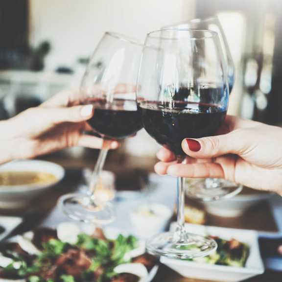 people holding up wine glasses over a table of food