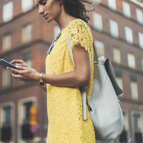 a woman in a yellow dress looking at her cell phone