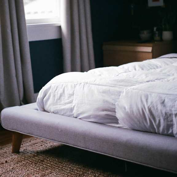 a bed with a white comforter and pillows in a bedroom