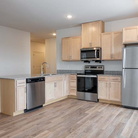 an empty kitchen with wooden cabinets and stainless steel appliances