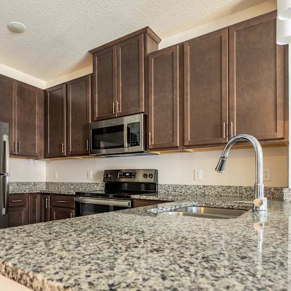 a kitchen with granite countertops and dark wood cabinets at sonder house, brooklyn center