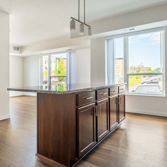 a kitchen and living room in an apartment with hardwood floors and a large window at sonder point 50+ apartments, brooklyn center, mn, 55430