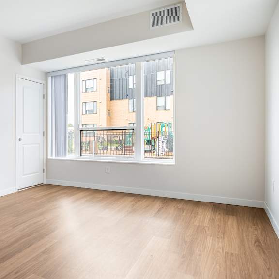 a bedroom with a large window and hardwood floors at sonder point 50+ apartments, minnesota, 55430