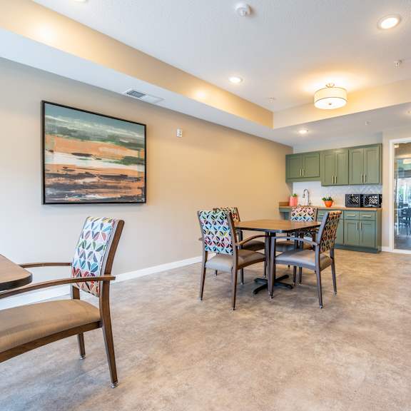 a dining area with a table and chairs and a kitchen in the background at sonder point 50+ apartments, minnesota, 55430