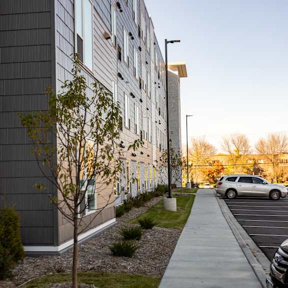 a sidewalk in front of a building with a tree next to it