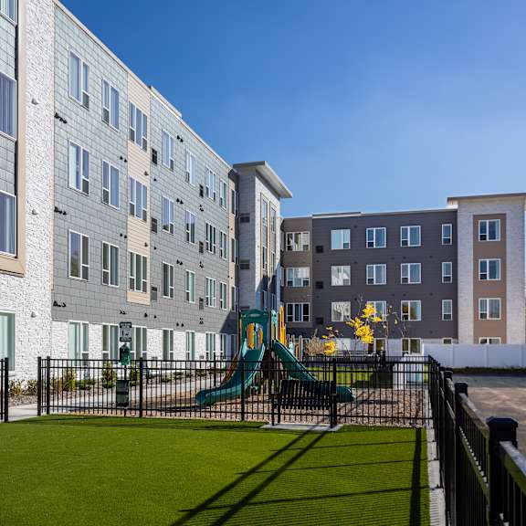 a playground in front of an apartment building with a play set
