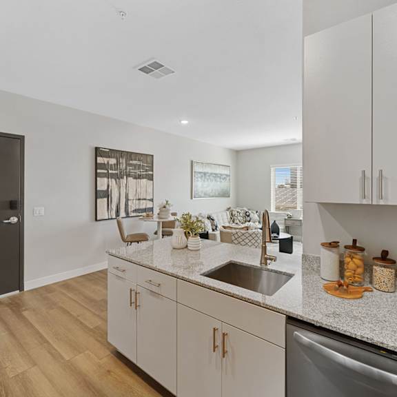 a kitchen with a sink, cabinets, and a fridge.