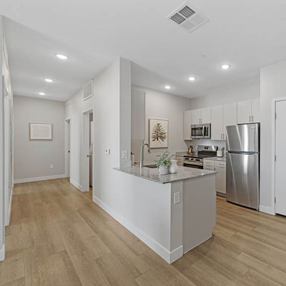 a kitchen with white cabinets and a wooden floor.