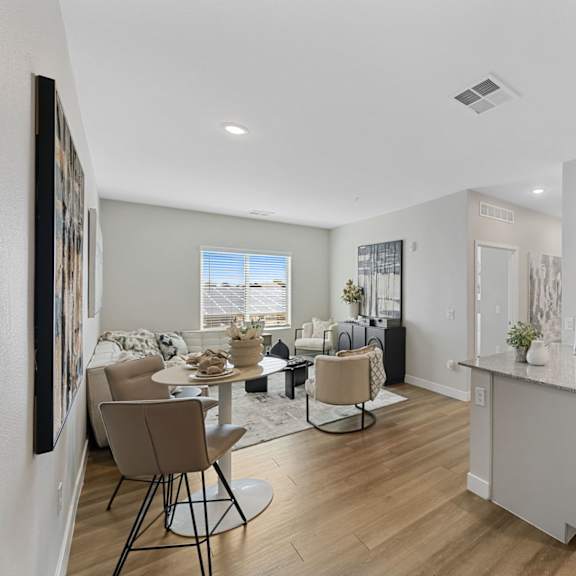 a well-lit, modern kitchen and dining area with wooden floors and white walls.
