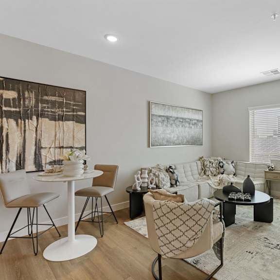 a living room with a white couch, a white table, and a painting on the wall.