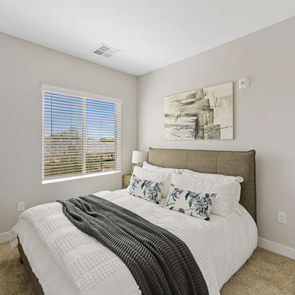 a bedroom with a large bed and a window with blinds.