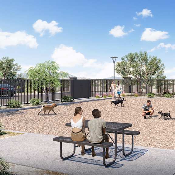 a group of people are sitting at a picnic table with their dogs in a park.