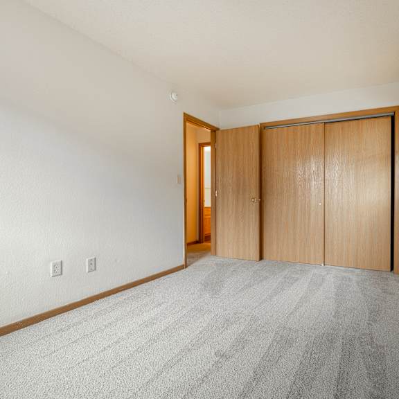 a spacious living room with carpet and a door to a bedroom at ames lake neighborhood apartments, st. paul, minnesota