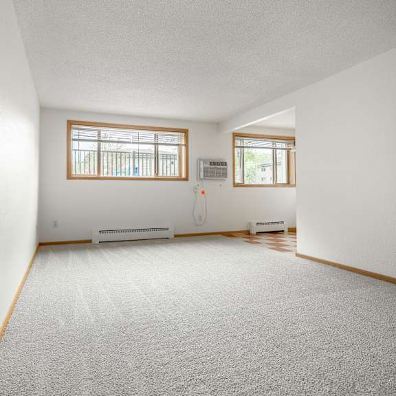 the living room and dining room of a house with white walls and a carpet at ames lake neighborhood apartments, st. paul