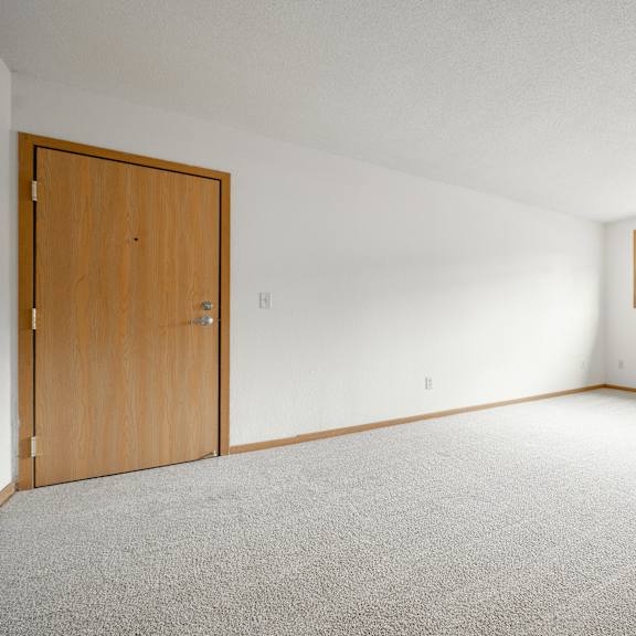 the living room of an empty house with a wooden door at ames lake neighborhood apartments, minnesota, 55106