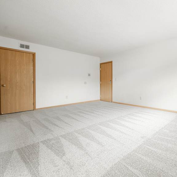 the living room of a house with a white floor and a wooden door at ames lake neighborhood apartments, st. paul, 55106