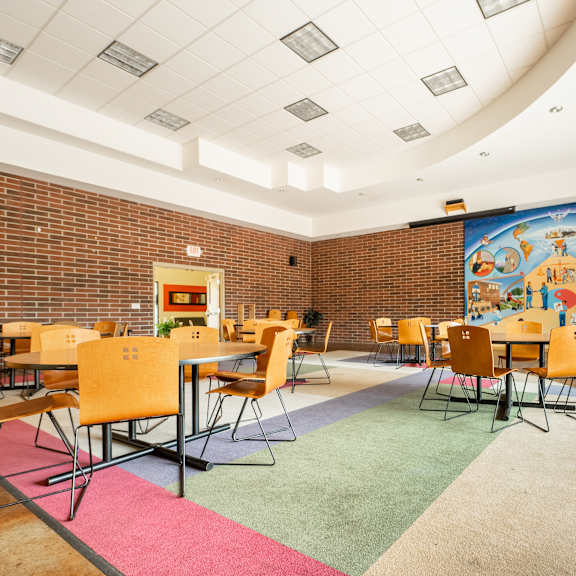 a dining room with tables and chairs and a mural on the wall at ames lake neighborhood apartments, st. paul, mn