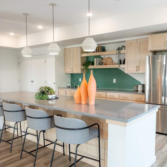 a modern kitchen with a long island and grey barstools.