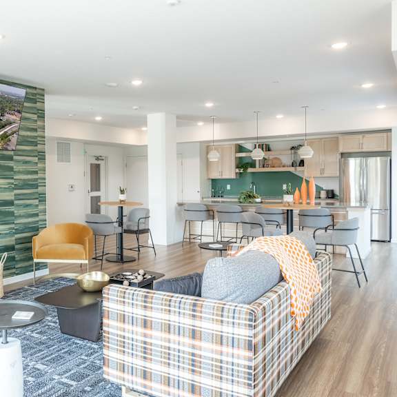 a living room with a plaid couch and a green wallpapered wall.