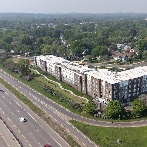 a large building with a white roof is surrounded by trees and a highway.