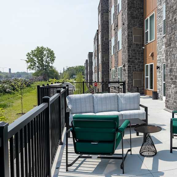 a patio with a green chair and a white couch.
