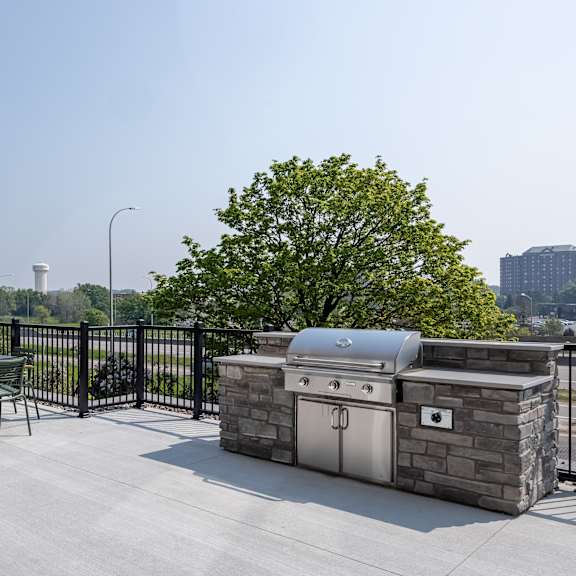 a bbq grill is on a patio with a table and chairs.