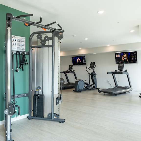 a gym with a variety of equipment including treadmills, stationary bikes, and weight machines.