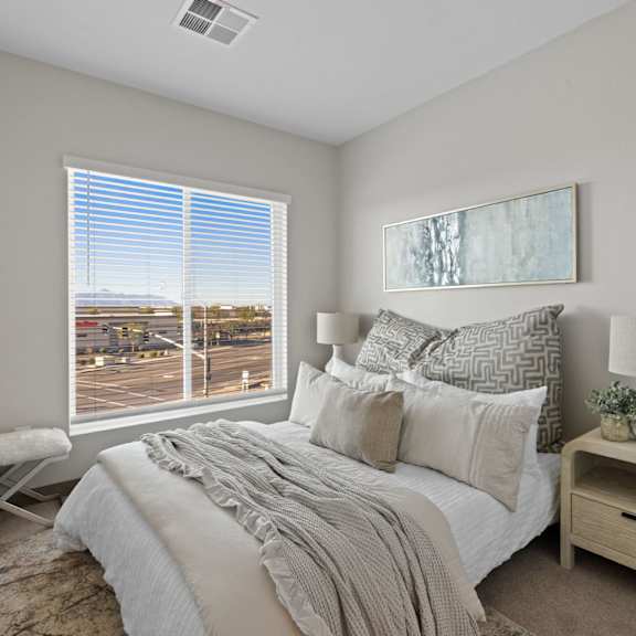 a bedroom with a large bed and a view of a parking lot outside the window at copa flats apartments, arizona