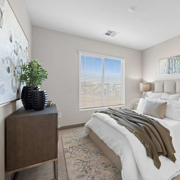 a bedroom with a large bed, a wooden nightstand, and a plant on a dresser at copa flats apartments, maricopa