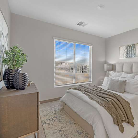 a bedroom with a large bed, a wooden dresser, and a painting on the wall at copa flats apartments, maricopa, 85138