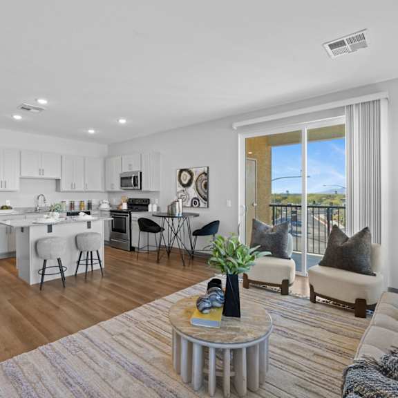 a modern kitchen with white cabinets and a dining area with a table and chairs at copa flats apartments, maricopa, arizona