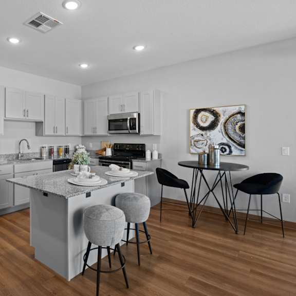 a modern kitchen with a large island and stools at copa flats apartments, maricopa, arizona