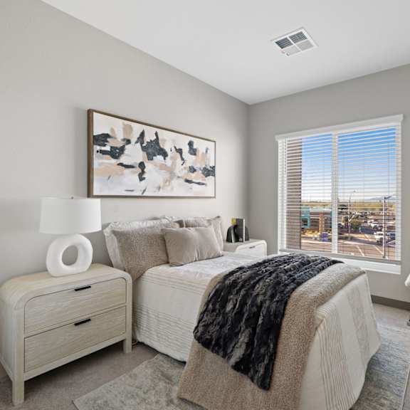 a bedroom with a large bed and a chair by the window at copa flats apartments, arizona, 85138