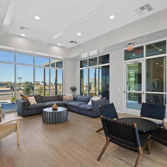 a living room with a grey couch, a black chair and a wooden table at copa flats apartments, arizona, 85138