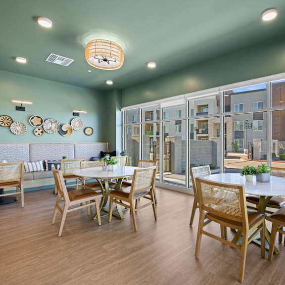 a dining room with a table set for four and a view of a building outside the window at copa flats apartments, maricopa, arizona