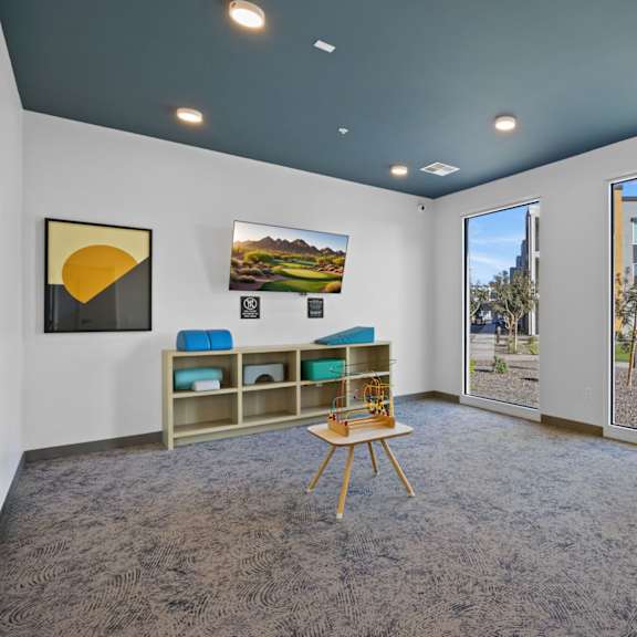 a room with a grey carpet and a wooden chair in front of a table at copa flats apartments, apartments, maricopa, az