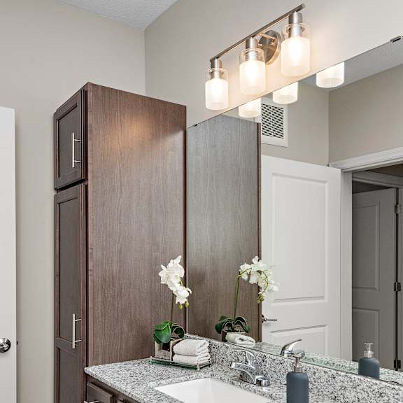 a bathroom with a sink, mirror, and wooden cabinets.at decatur landing i & ii, minnesota, 55445