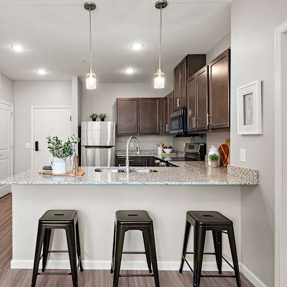 a kitchen with a granite countertop and bar stools.at decatur landing i & ii, brooklyn park, 55445