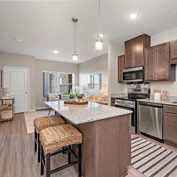 a kitchen with brown cabinets and a white island.at decatur landing i & ii, brooklyn park minnesota