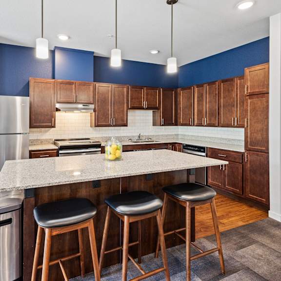a kitchen with a large island with three stools at eastgate apartments, minnesota, 55904