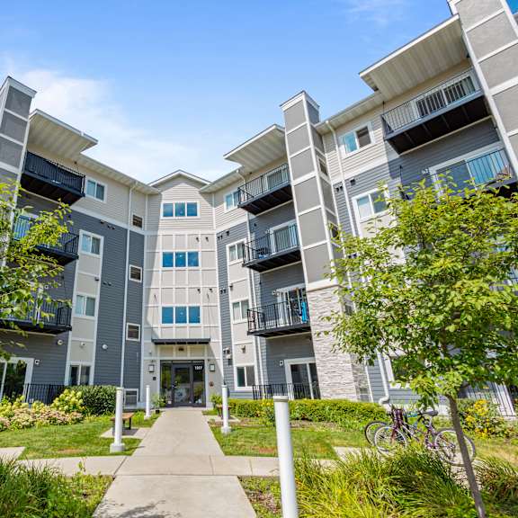 an exterior view of an apartment building with trees and a sidewalk at eastgate apartments, rochester, mn