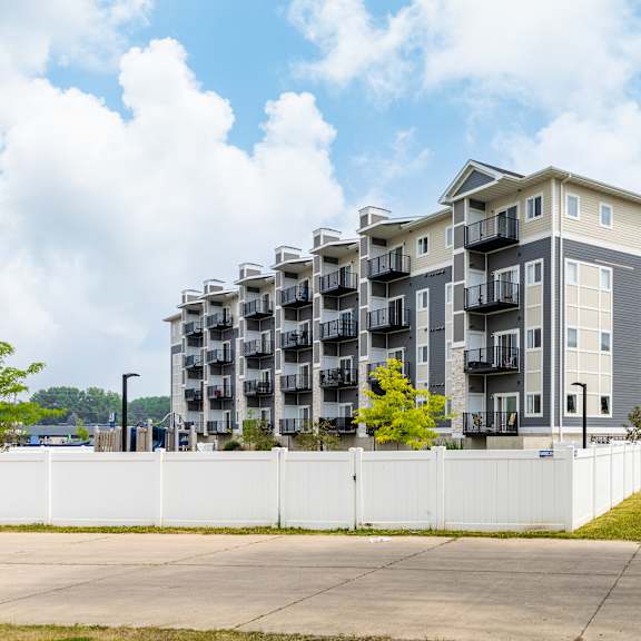 a grey apartment building with balconies and a white fence in front of it at eastgate apartments, minnesota, 55904