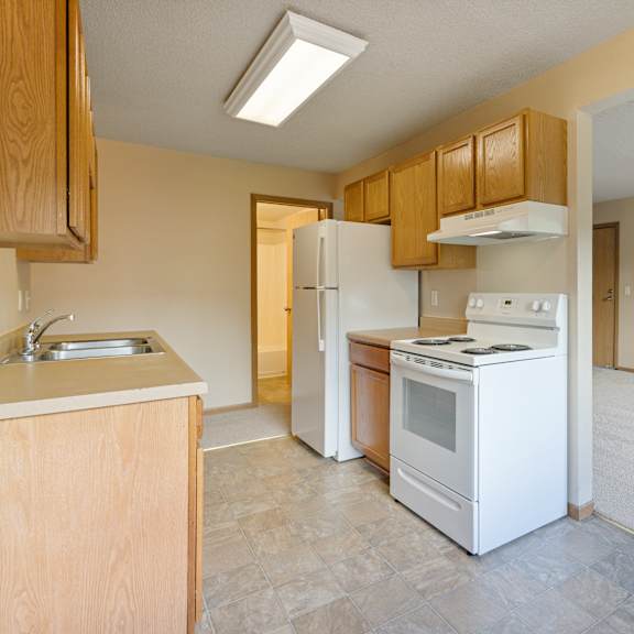 a kitchen with white appliances and wooden cabinets at ames lake neighborhood apartments, st paul