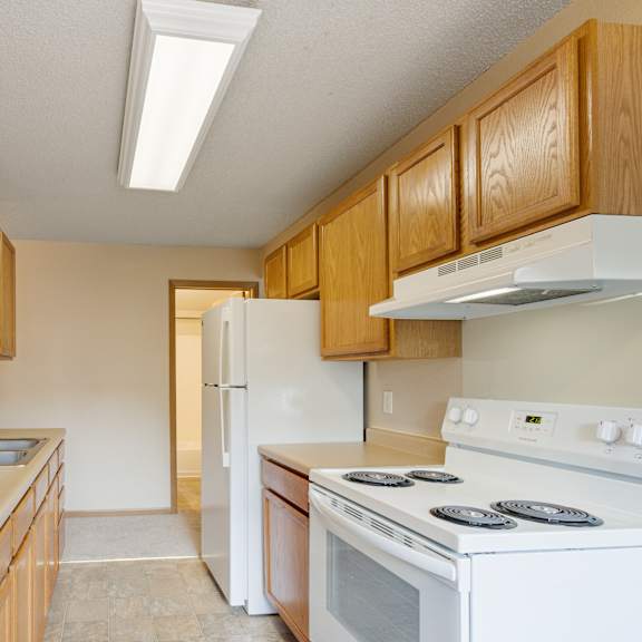 a kitchen with wooden cabinets and a white stove top oven at ames lake neighborhood apartments, st paul, minnesota