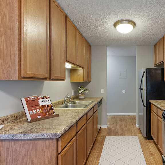 a kitchen with wooden cabinets and a granite counter top at heritage hills apartments, minnesota, 55437