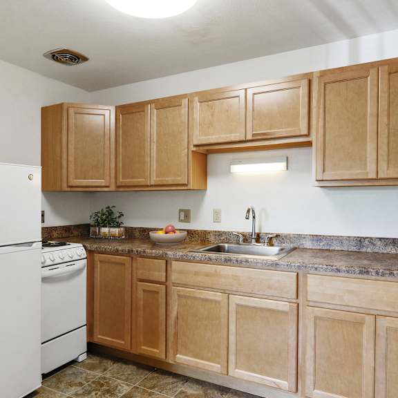 a kitchen with wooden cabinets and a white refrigerator at humboldt senior 55+ apartments, saint paul, mn