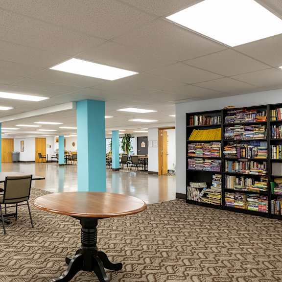 a large library with tables and chairs and bookshelves at humboldt senior 55+ apartments, saint paul, mn, 55107
