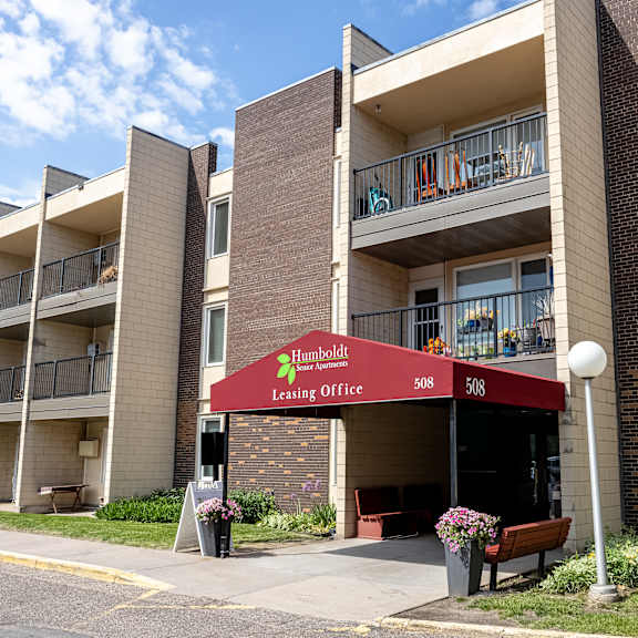 an apartment building with a red awning in front of it at humboldt senior 55+ apartments, minnesota
